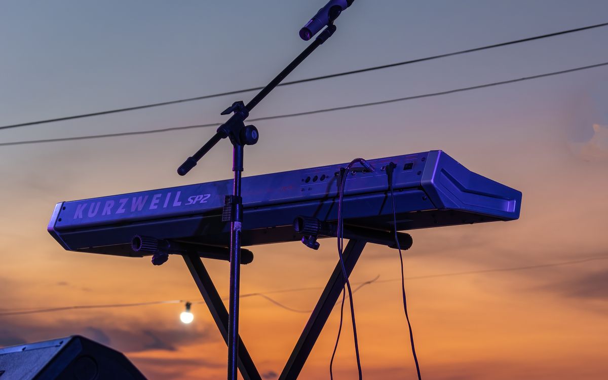 A piano and microphone on a stage on a beach at sunset