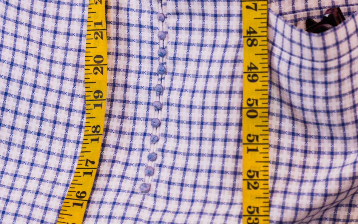 A size chart and a tape measure on a worktable beside a folded shirt