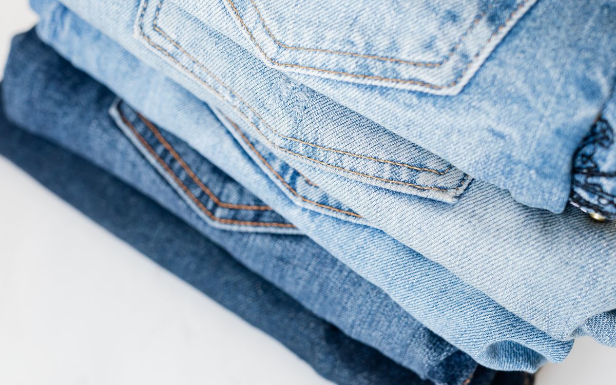 A stack of folded jeans on a white marble surface