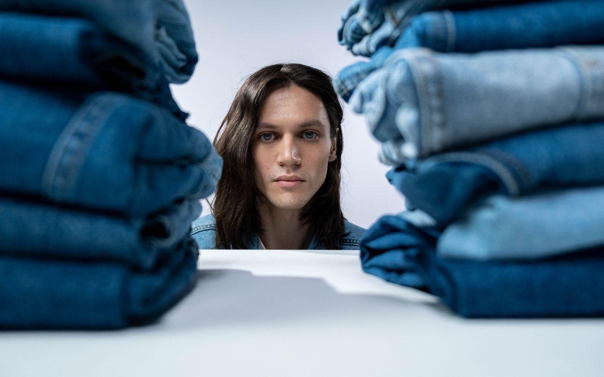 A man looking at folded jeans in a wooden cabinet