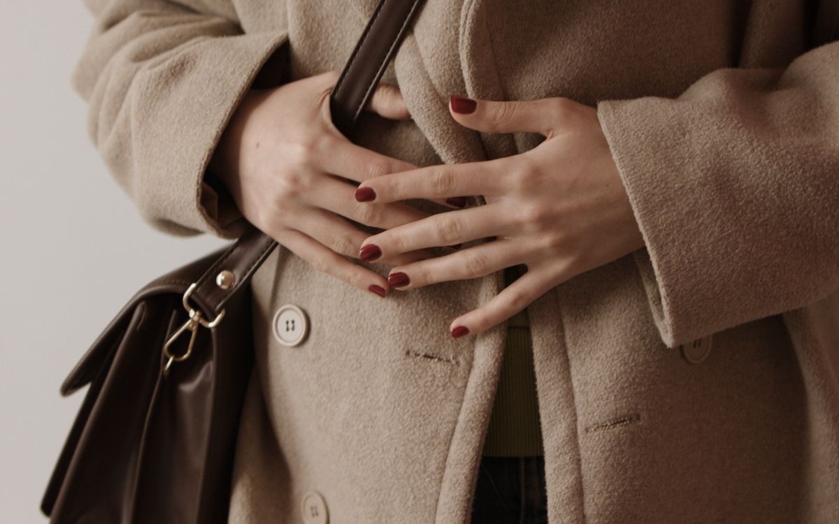 An elegant woman in a beige overcoat with a handbag