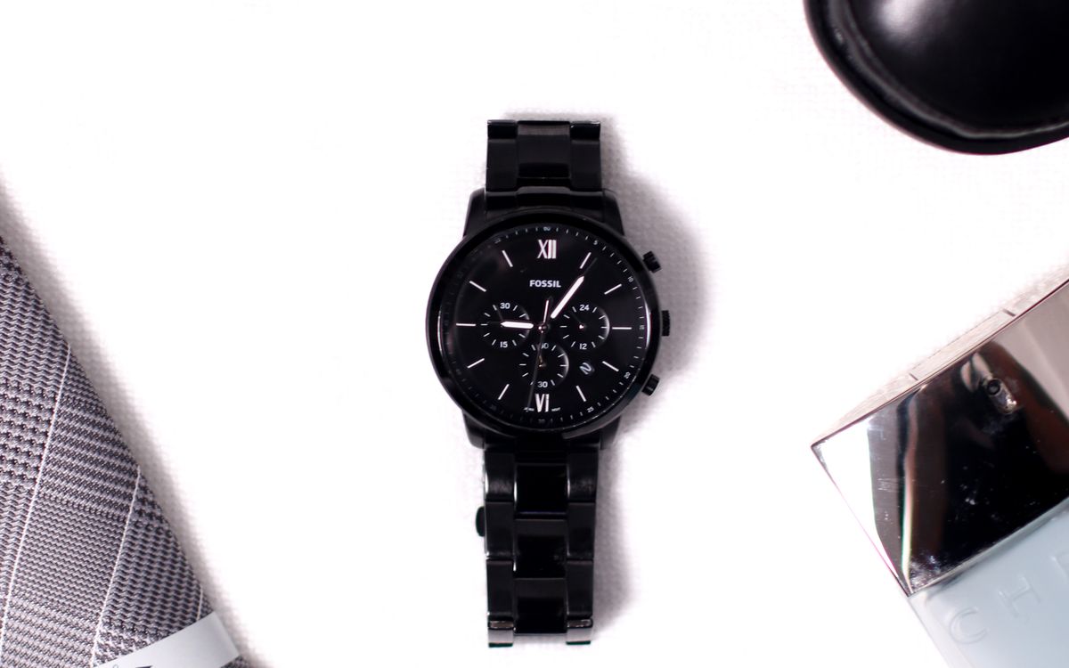 A black round analog watch on a white surface